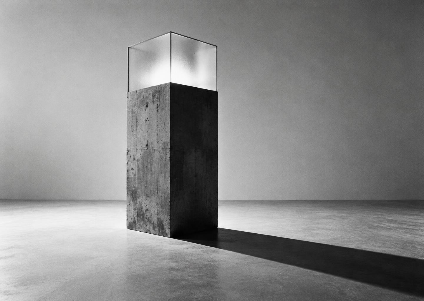 A concrete monolith topped with frosted glass, casting a long shadow
